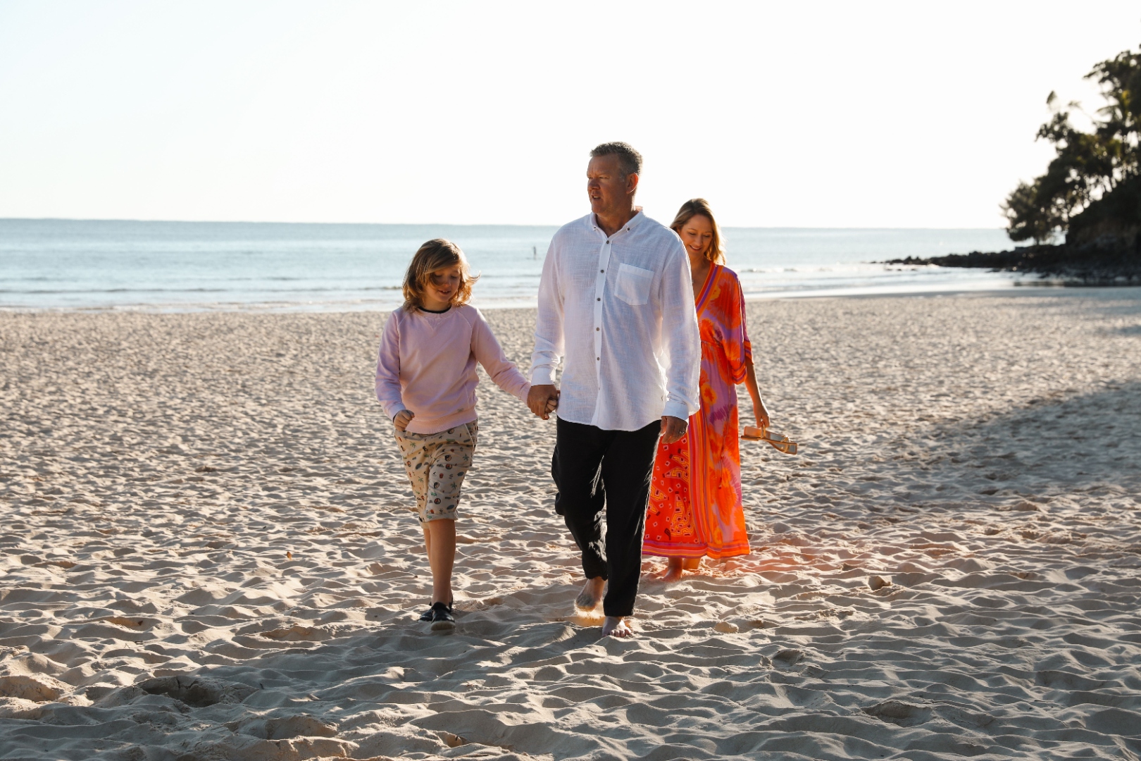 Craig Swanger walking on Noosa beach with Trenna and their child, June 2022