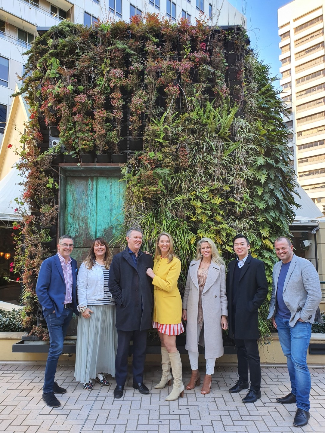 Craig, Trenna and the Super Fierce team in front of a vertical garden wall