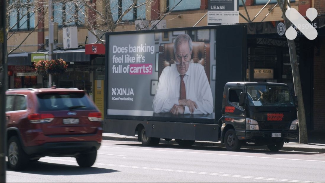 A Xinja mobile billboard truck on a city street reading 'Does banking feel like it's full of can'ts?' with the Xinja logo and hashtag CantFreeBanking